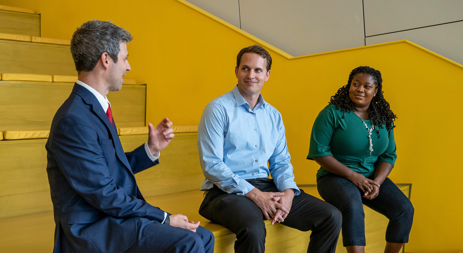 Two Master of Accounting students talking to a professor in the Hunt Library
