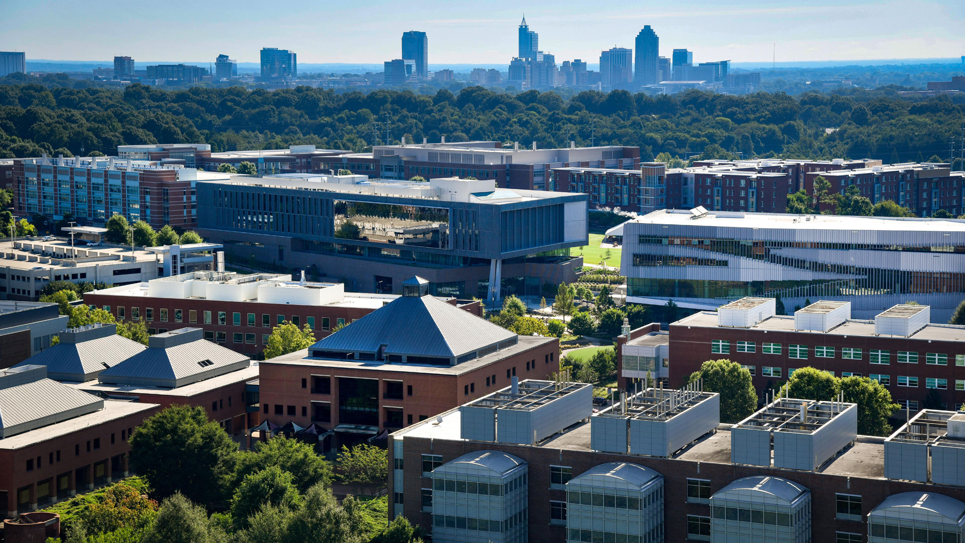 A photo highlighting the many buildings on Centennial Campus, in relation to downtown Raleigh skyline.