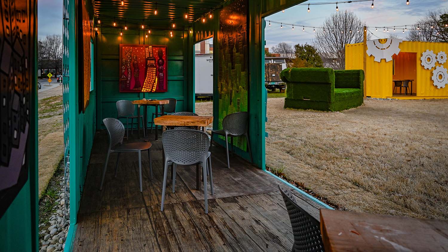 An interior view of the aqua container, filled with intimate seating and warm string lights.