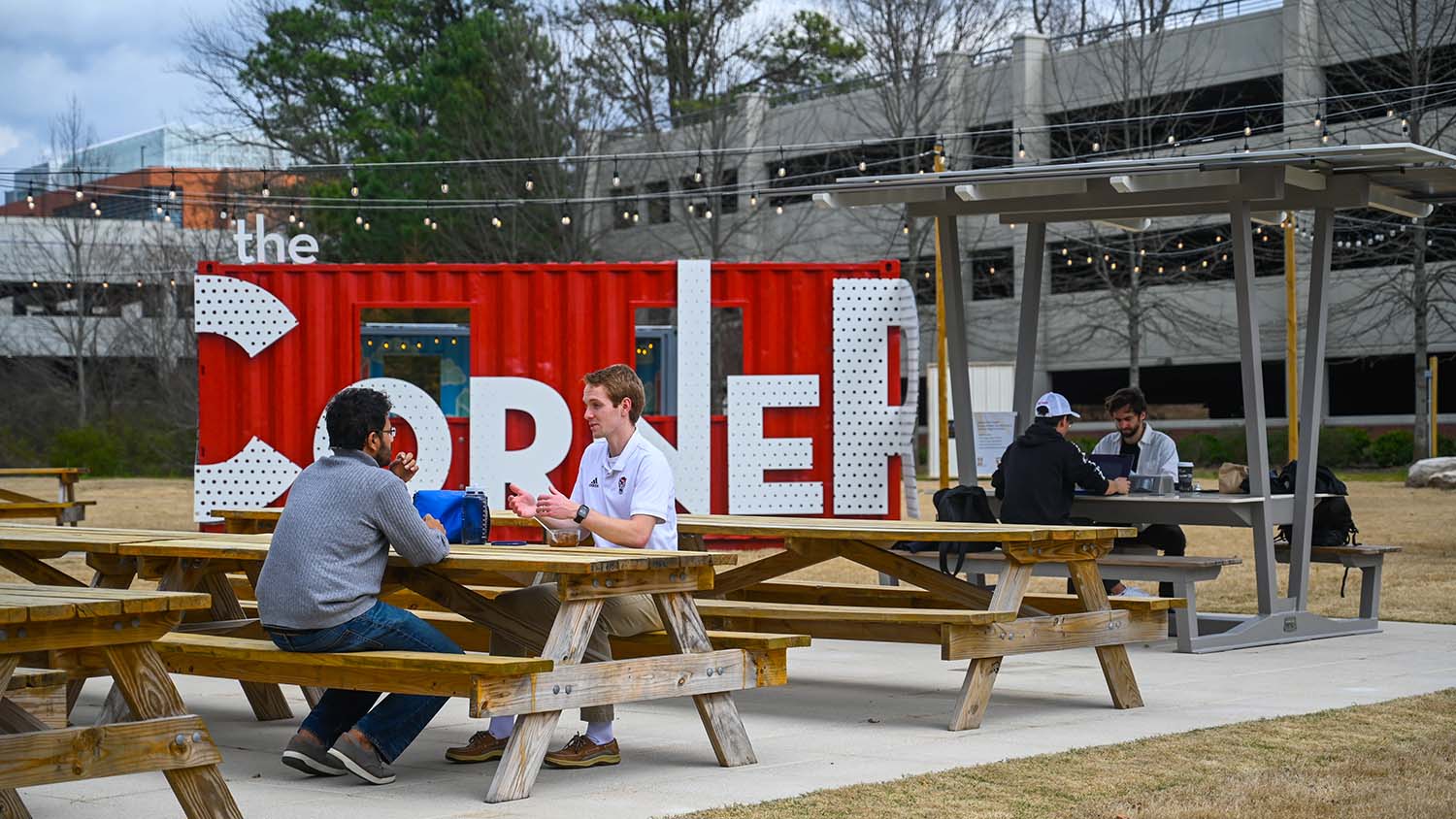 Students gather and work together at picnic tables in the center of The Corner.