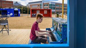 A young man plays the brightly painted piano on The Corner's main stage.