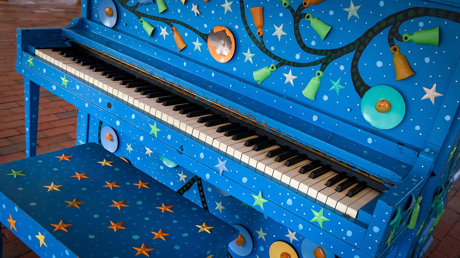 A piano painted cobalt blue and decorated with stars, located on The Corner's main stage.
