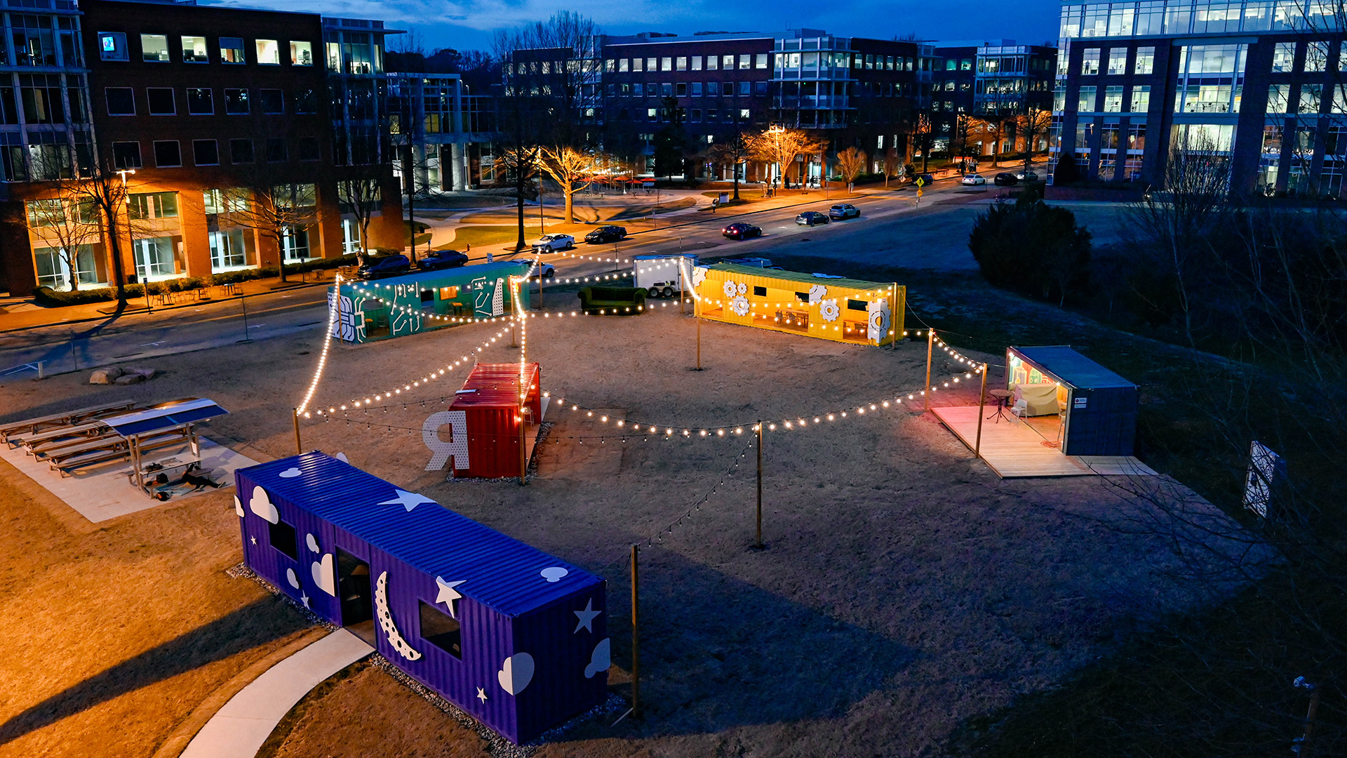 An aerial view of The Corner at night, lit by twinkling string lights.