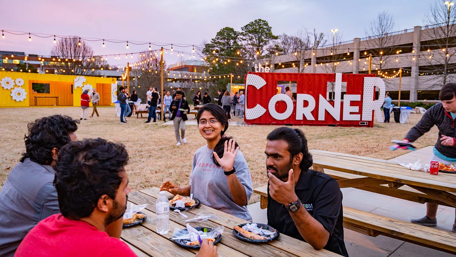 Students eat at picnic tables during a food truck rodeo at The Corner.